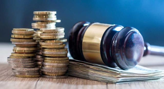 Condonaciones de deudas en fundaciones: tratamiento contable según el ICAC. Imagen de un martillo y monedas de euros amontonadas